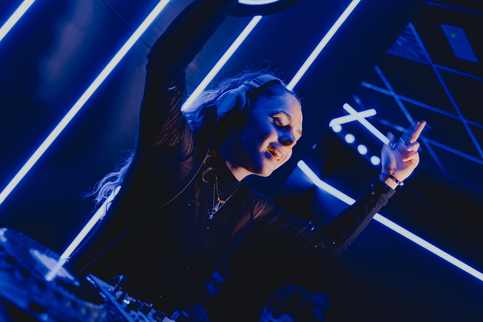 MAR SALVA raising her hands while performing under electric blue lights